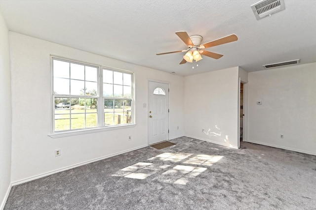 interior space with ceiling fan, dark carpet, and a textured ceiling