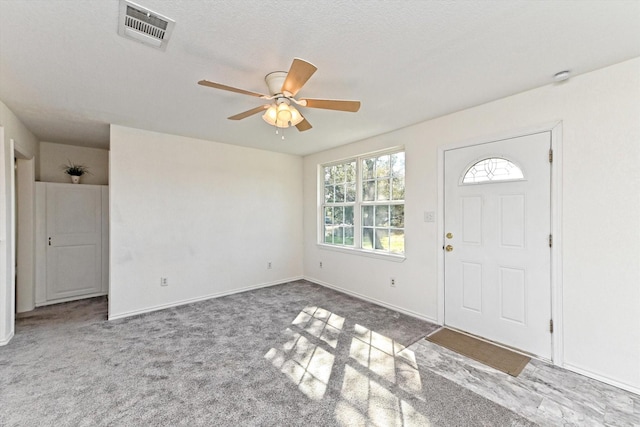 carpeted foyer entrance featuring ceiling fan and a textured ceiling