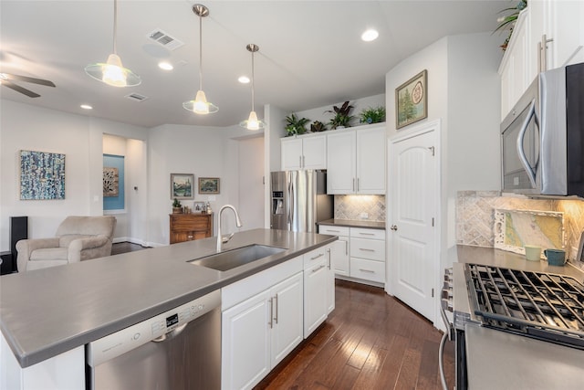 kitchen with appliances with stainless steel finishes, white cabinetry, decorative backsplash, sink, and a center island with sink