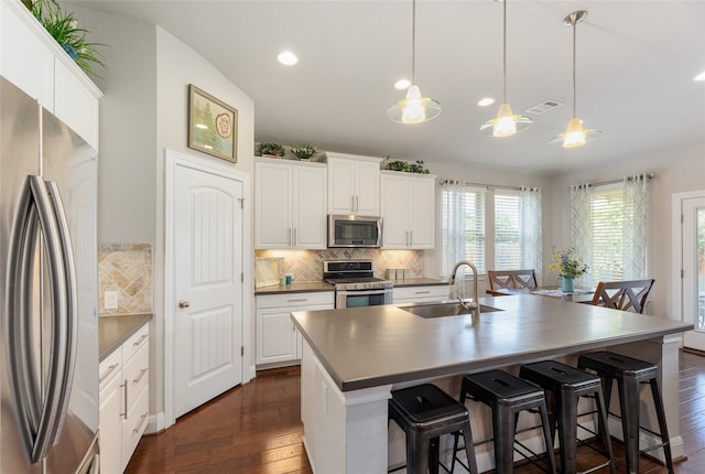 kitchen with pendant lighting, sink, white cabinetry, a kitchen island with sink, and appliances with stainless steel finishes