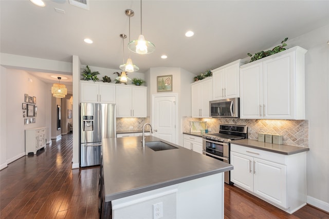 kitchen with white cabinets, appliances with stainless steel finishes, decorative light fixtures, an island with sink, and sink