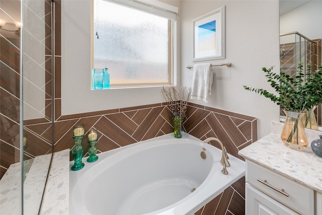 bathroom featuring tiled bath and vanity