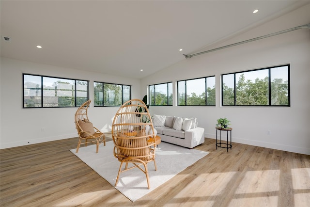 living room featuring light hardwood / wood-style floors, a healthy amount of sunlight, and vaulted ceiling