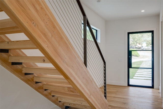 stairway with a healthy amount of sunlight and wood-type flooring