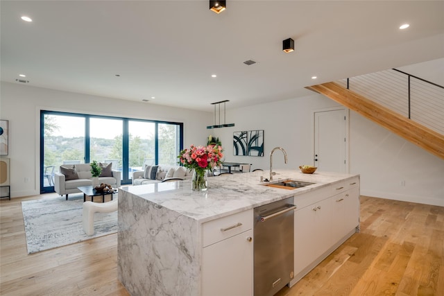 kitchen featuring light stone countertops, sink, white cabinetry, and a kitchen island with sink