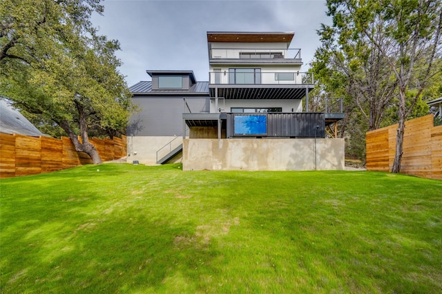 rear view of property with a balcony and a lawn