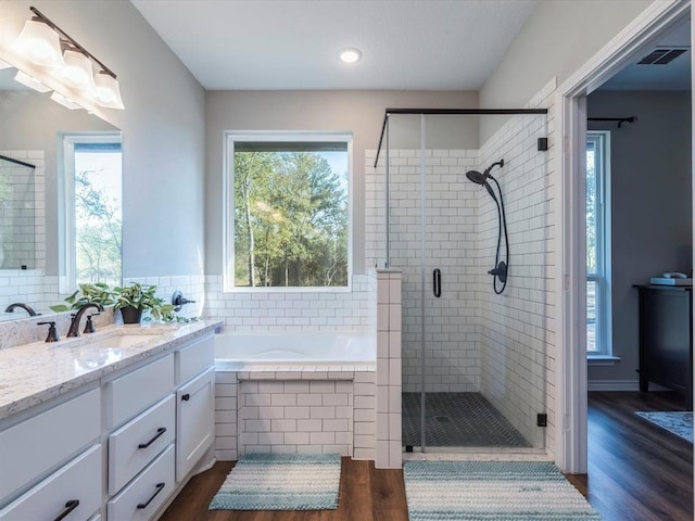 bathroom featuring plus walk in shower, hardwood / wood-style floors, and vanity