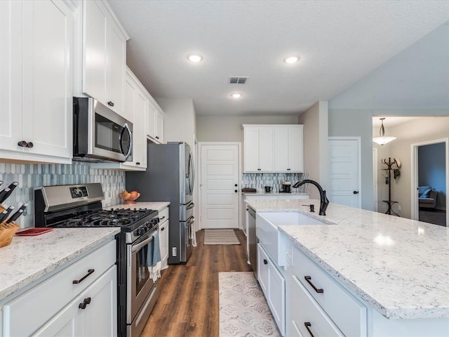 kitchen featuring a kitchen island with sink, decorative backsplash, stainless steel appliances, and white cabinetry