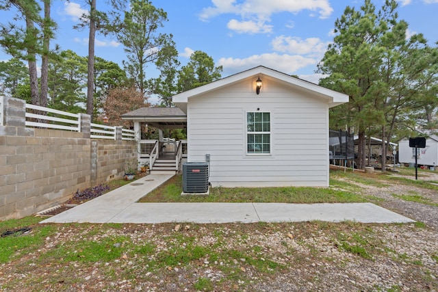 view of side of property with central AC unit and a trampoline