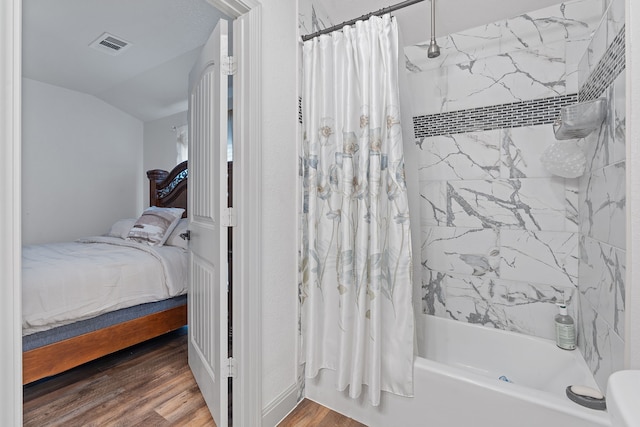 bathroom featuring vaulted ceiling, shower / bath combination with curtain, and hardwood / wood-style flooring