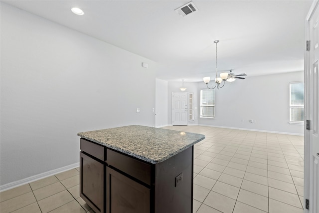 kitchen with ceiling fan with notable chandelier, dark brown cabinetry, a center island, decorative light fixtures, and light tile patterned flooring