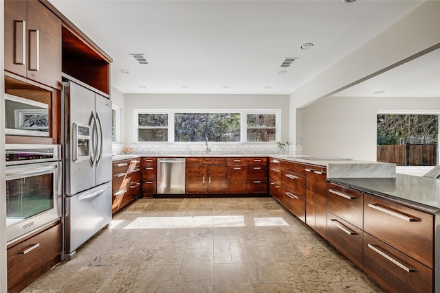 kitchen with appliances with stainless steel finishes, kitchen peninsula, tasteful backsplash, and sink