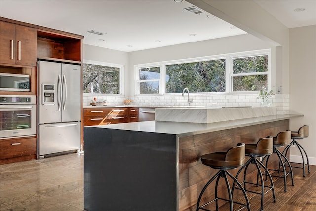 kitchen with a breakfast bar area, kitchen peninsula, plenty of natural light, and stainless steel appliances