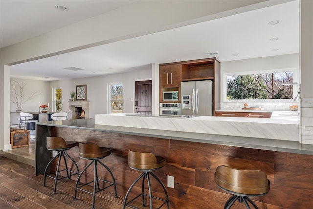 kitchen with dark wood-type flooring, a breakfast bar area, appliances with stainless steel finishes, and plenty of natural light