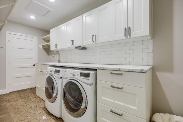 clothes washing area with washing machine and dryer, sink, and cabinets