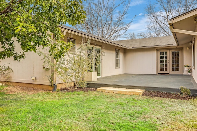 rear view of property with a wooden deck, a lawn, and french doors