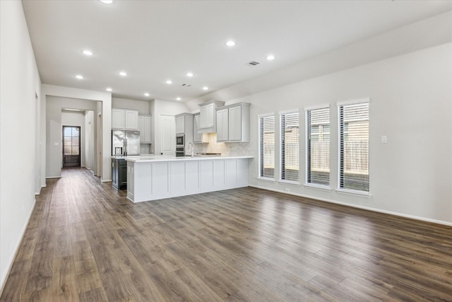 kitchen featuring appliances with stainless steel finishes, tasteful backsplash, dark wood-type flooring, white cabinets, and sink