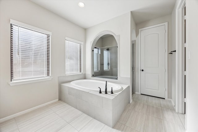 bathroom with tile patterned floors and a relaxing tiled tub