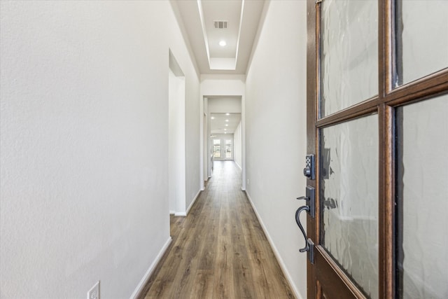 hallway with a raised ceiling and hardwood / wood-style flooring