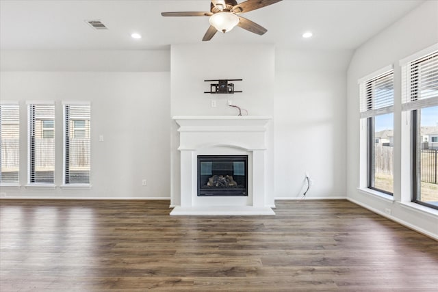 unfurnished living room featuring dark wood-type flooring, ceiling fan, and plenty of natural light