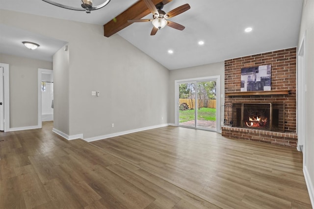 unfurnished living room featuring ceiling fan, vaulted ceiling with beams, a fireplace, and hardwood / wood-style flooring