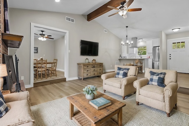 living room featuring ceiling fan with notable chandelier, light hardwood / wood-style flooring, and vaulted ceiling with beams