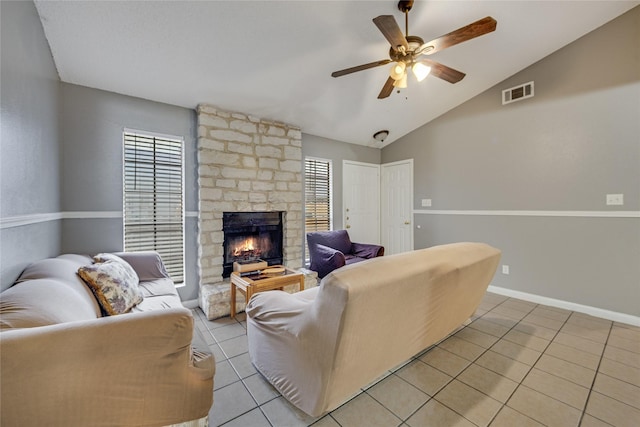 tiled living room featuring ceiling fan, plenty of natural light, lofted ceiling, and a stone fireplace