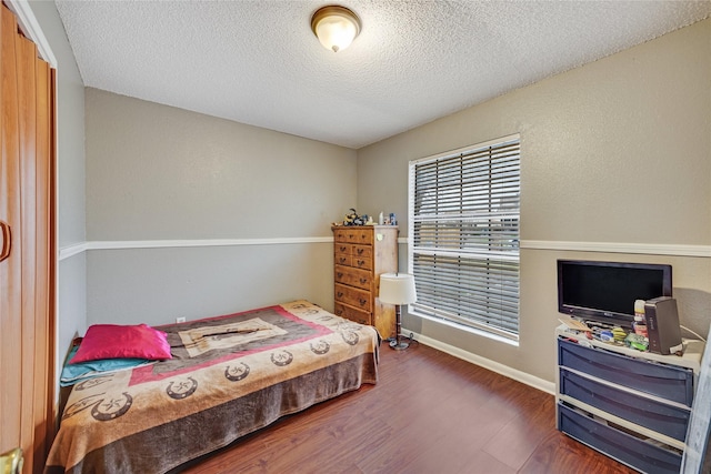 bedroom with a textured ceiling and dark hardwood / wood-style flooring