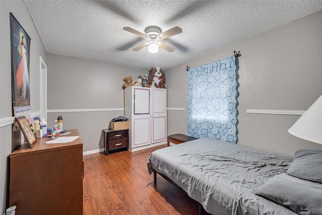 bedroom featuring ceiling fan, wood-type flooring, and a textured ceiling