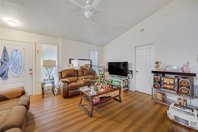 living room with hardwood / wood-style flooring, a textured ceiling, lofted ceiling, and ceiling fan