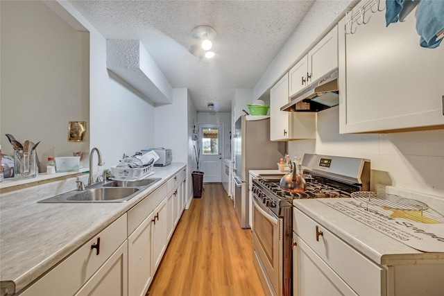 kitchen featuring a textured ceiling, white cabinets, stainless steel gas range, sink, and light hardwood / wood-style flooring