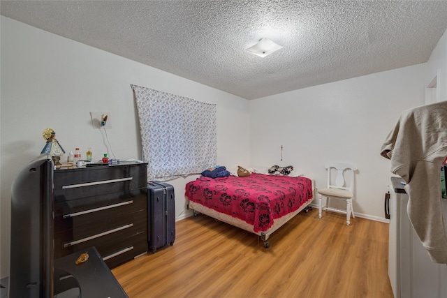 bedroom featuring a textured ceiling and light hardwood / wood-style flooring