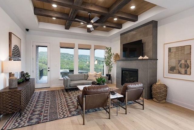 living room with ceiling fan, a fireplace, light hardwood / wood-style floors, beamed ceiling, and wooden ceiling