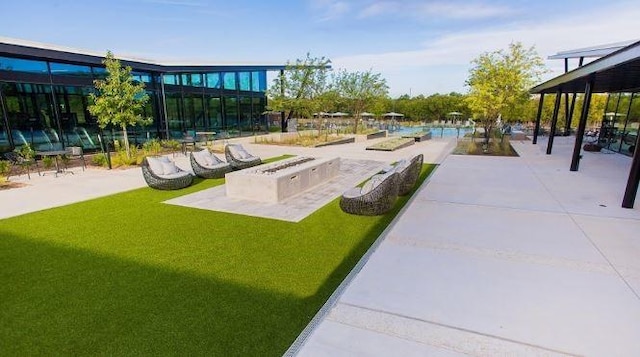 view of community featuring a lawn, a fire pit, and a patio