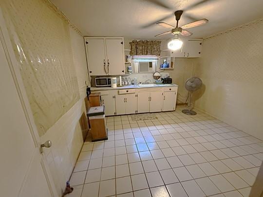 kitchen featuring ceiling fan, light tile patterned floors, sink, and white cabinetry