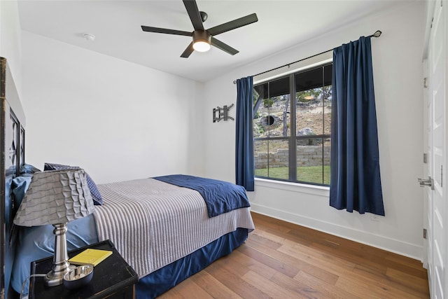 bedroom with ceiling fan, multiple windows, and hardwood / wood-style floors