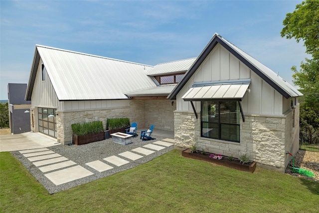 back of house with an outdoor fire pit and a yard