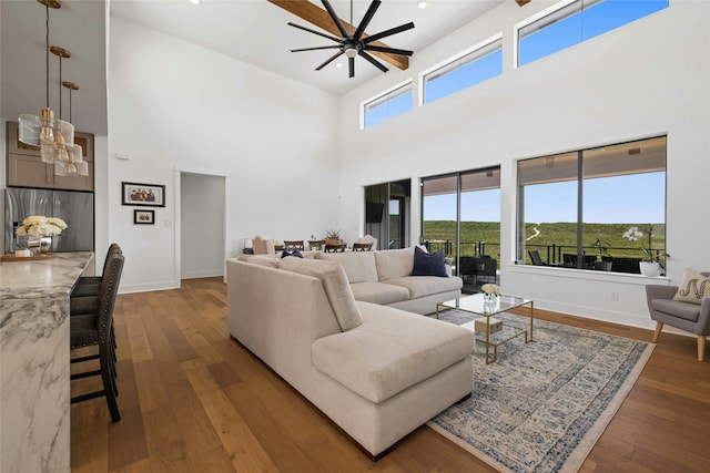 living room with ceiling fan, dark wood-type flooring, and a high ceiling