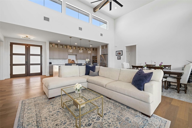 living room featuring ceiling fan, a towering ceiling, and hardwood / wood-style flooring