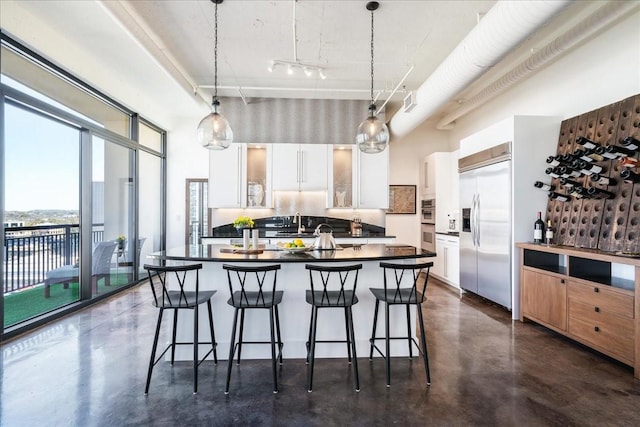 kitchen with pendant lighting, appliances with stainless steel finishes, white cabinetry, sink, and a breakfast bar