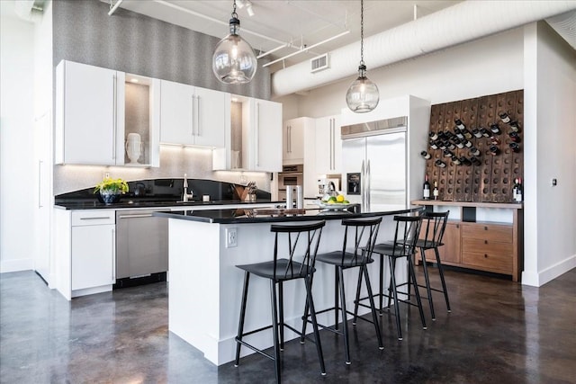 kitchen featuring white cabinetry, stainless steel appliances, a kitchen breakfast bar, hanging light fixtures, and a kitchen island