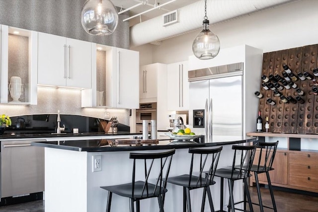 kitchen with decorative light fixtures, a center island, sink, white cabinetry, and appliances with stainless steel finishes