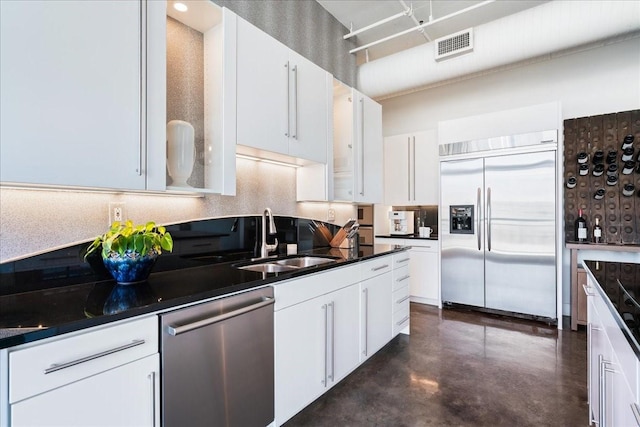 kitchen featuring stainless steel appliances, backsplash, white cabinetry, and sink