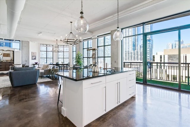 kitchen featuring white cabinets, a center island, decorative light fixtures, a kitchen bar, and black electric stovetop