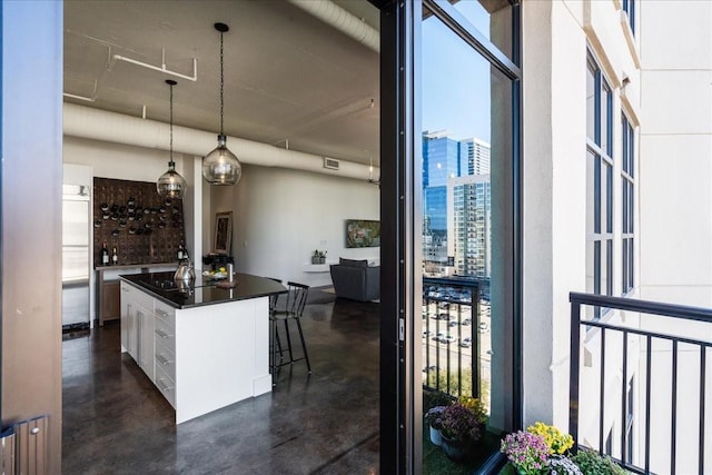 kitchen featuring a breakfast bar area, hanging light fixtures, white cabinetry, and a kitchen island