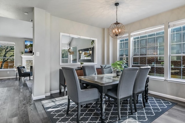 dining space featuring an inviting chandelier, dark hardwood / wood-style flooring, and a fireplace