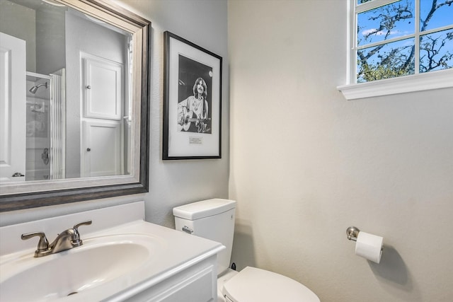 bathroom featuring toilet, vanity, and a shower with shower door