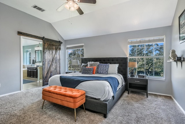 bedroom with ceiling fan, a barn door, vaulted ceiling, carpet floors, and connected bathroom