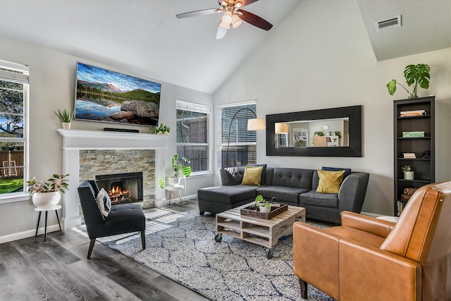 living room featuring ceiling fan, high vaulted ceiling, a stone fireplace, and hardwood / wood-style flooring