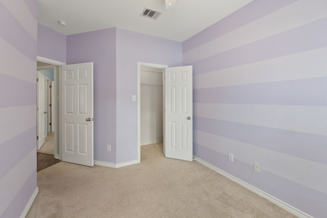 unfurnished bedroom featuring light carpet and a closet